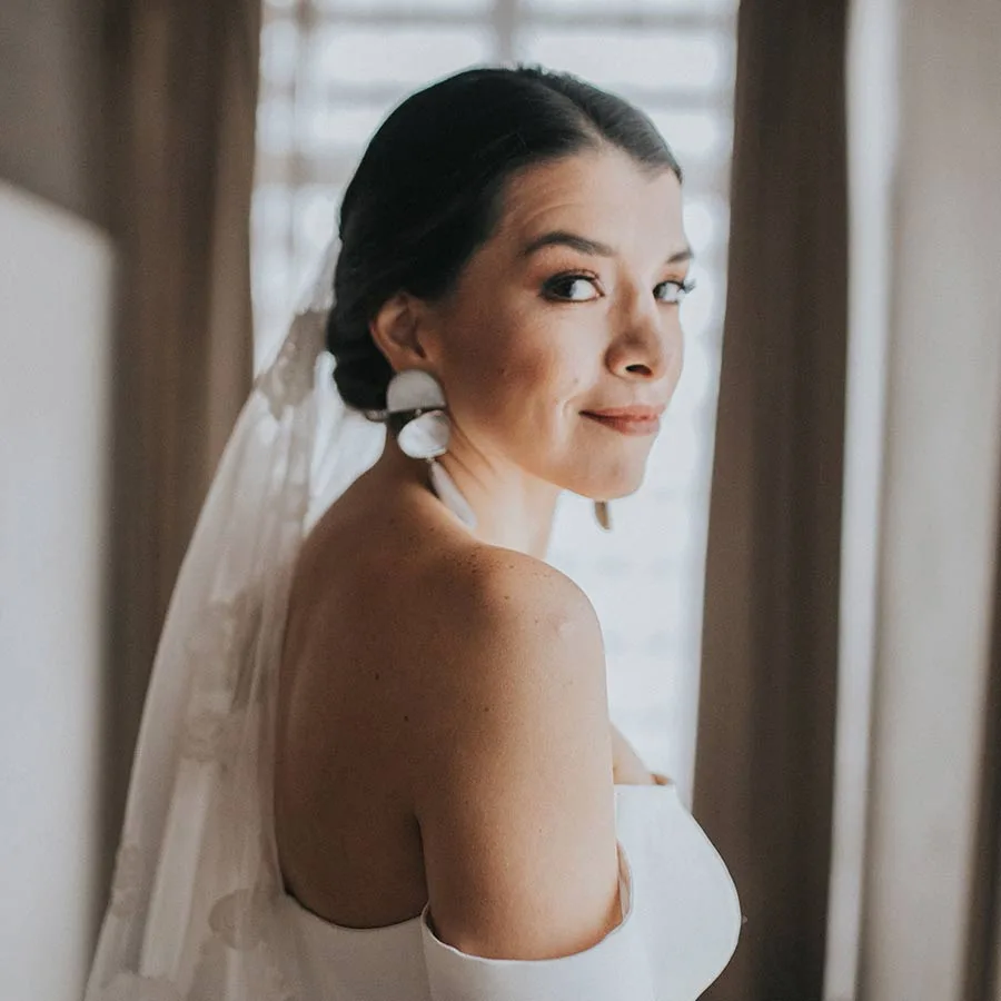 Elegante recogido nupcial y maquillaje luminoso con aretes protagonistas