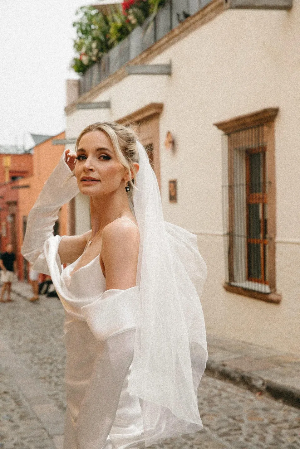 Novia con maquillaje natural y velo al viento en una calle de San Miguel