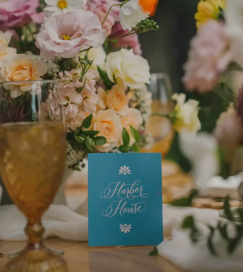 Centro floral pastel y cristalería ámbar sobre una mesa de boda