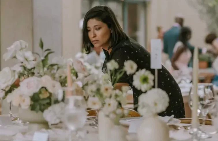 Profesional de eventos de ZUMO revisando una mesa de recepción con flores blancas