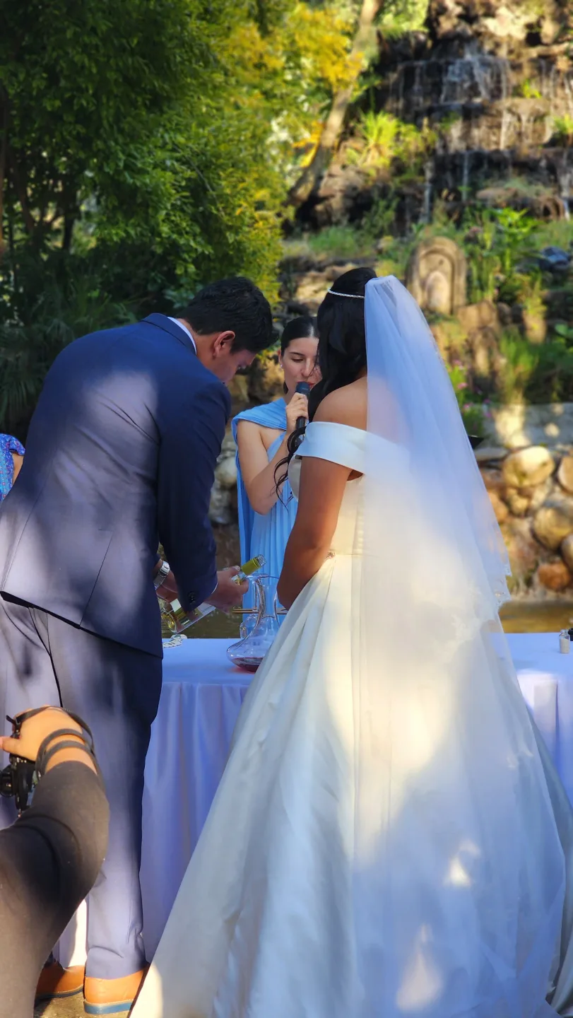 Oficiante guiando una boda simbólica junto a una cascada de jardín