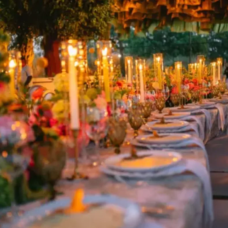 Mesa de boda iluminada con velas y arreglos florales coloridos diseñada por Penzi Weddings
