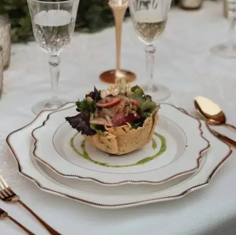 Platillo de boda presentado con cristalería fina y cubiertos dorados