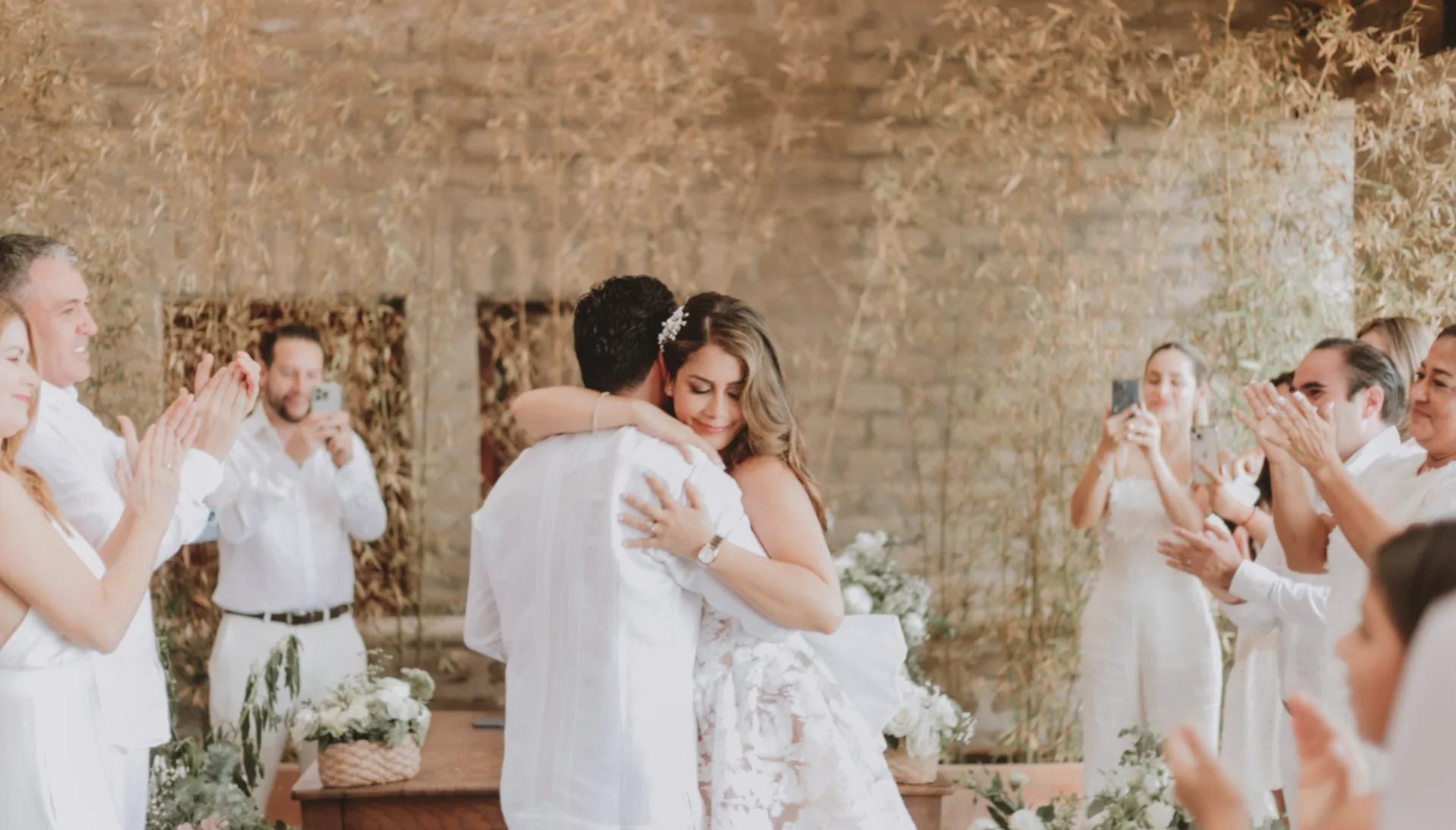 Recién casados abrazándose durante una ceremonia íntima rodeados de sus invitados