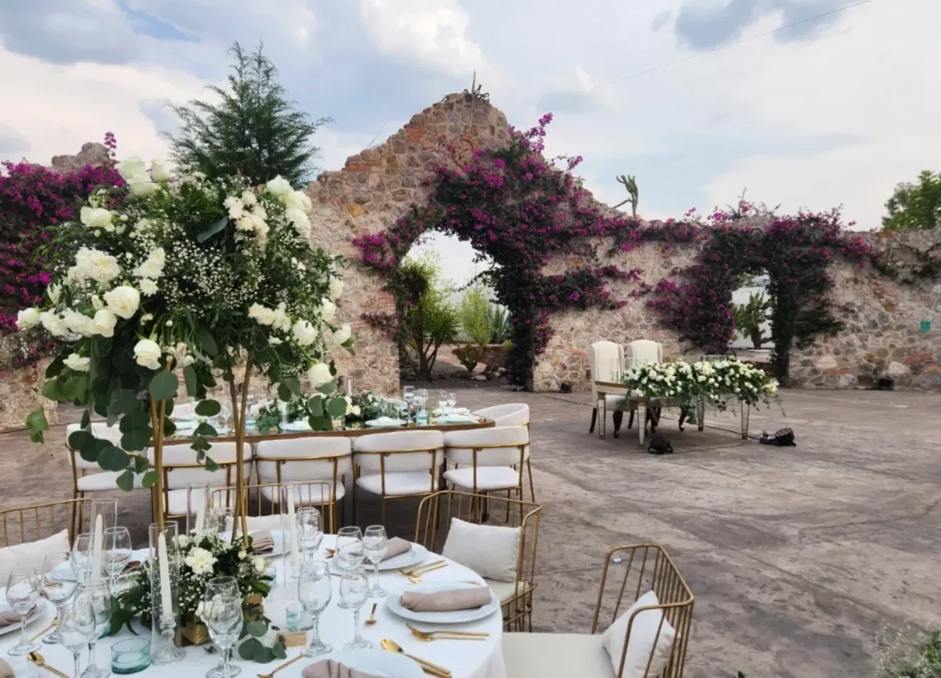 Montaje de recepción al aire libre en blanco y verde en el patio de arcos de piedra de Hacienda Agualuna