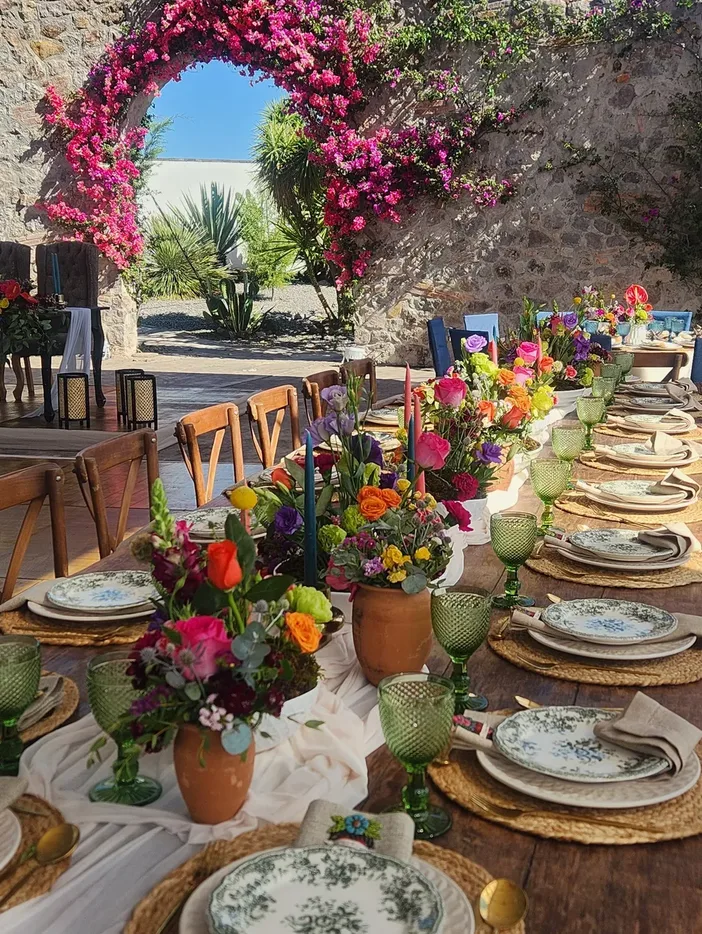 Mesa de boda colorida junto a un arco cubierto de buganvilias en Hacienda Agualuna