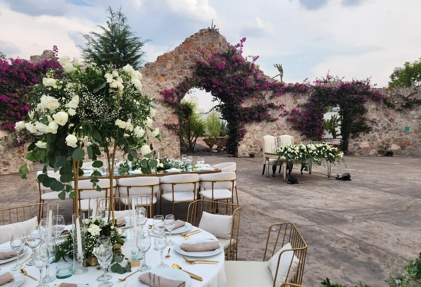 Recepción de boda al aire libre bajo arcos de piedra cubiertos de buganvilias en Hacienda Agualuna