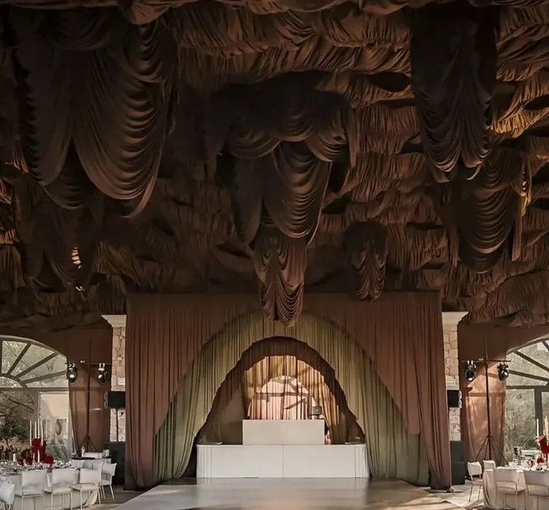 Recepción de boda interior con telas decorativas y pista de baile central