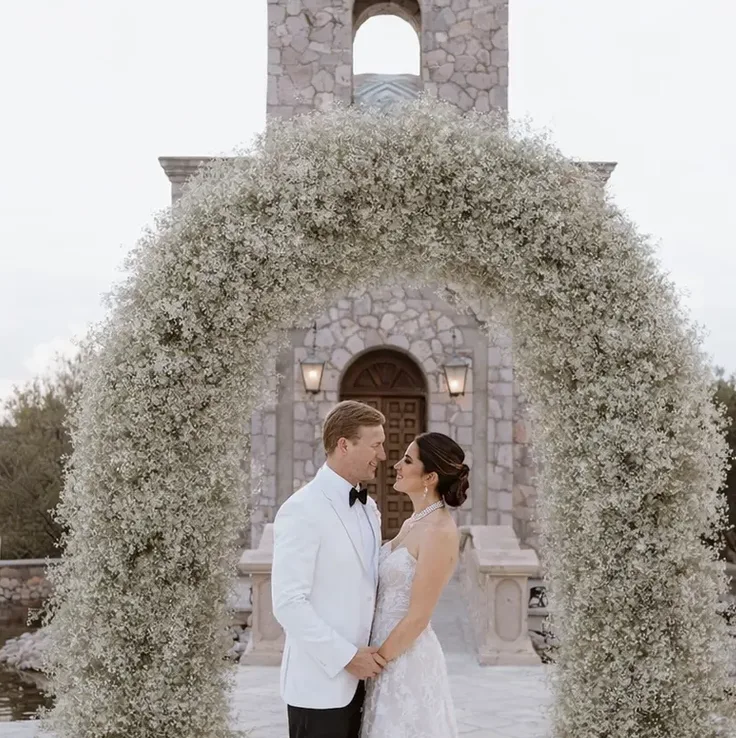 Recién casados bajo un arco floral frente a la capilla privada