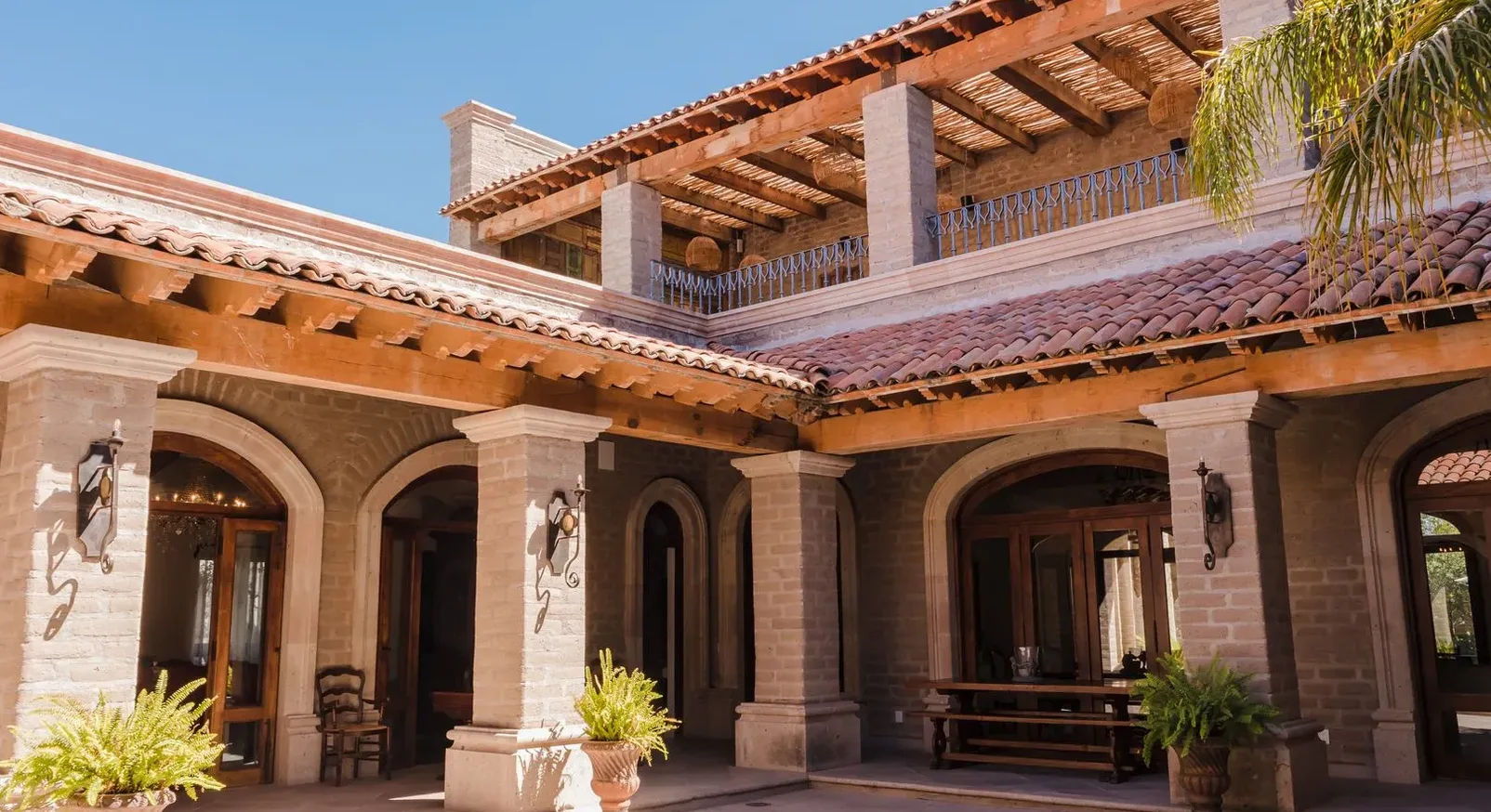 Patio colonial con arcos de piedra y terrazas techadas