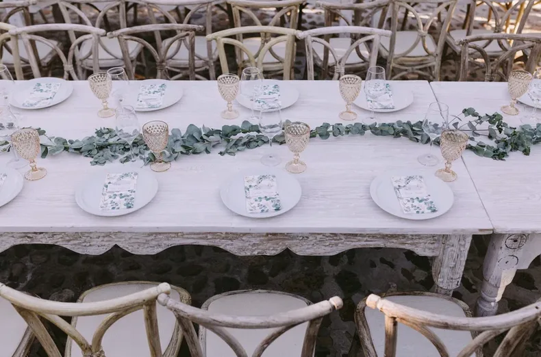 Mesa rústica de boda preparada con vajilla blanca y follaje