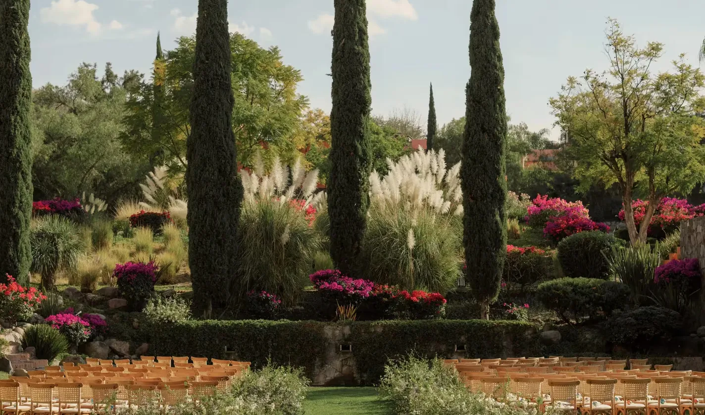 Ceremonia de boda en el jardín enmarcada por cipreses en Rosewood San Miguel de Allende